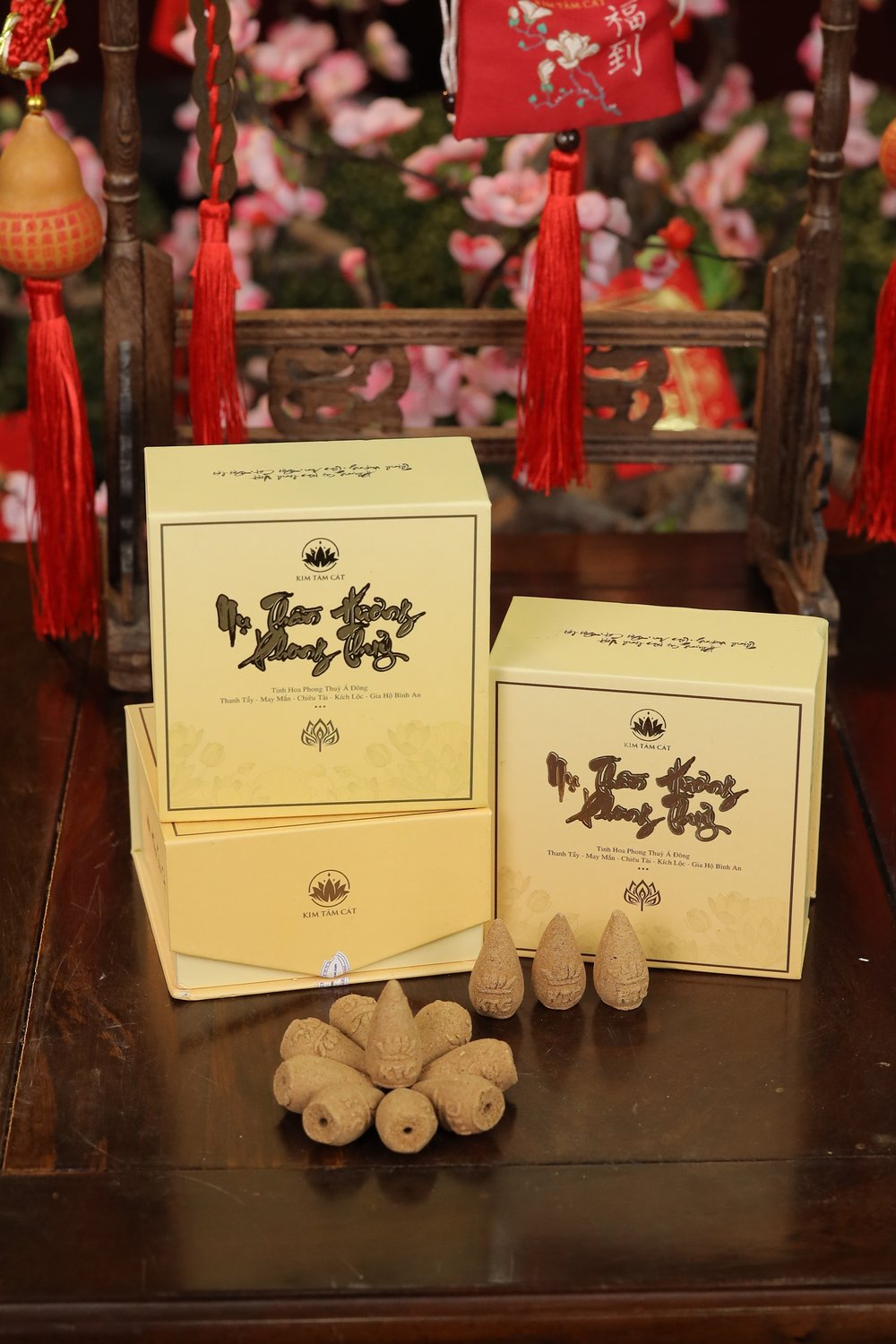 Hai hộp nụ Thần Hương và nhiều nụ hương bày trước nền hoa đào