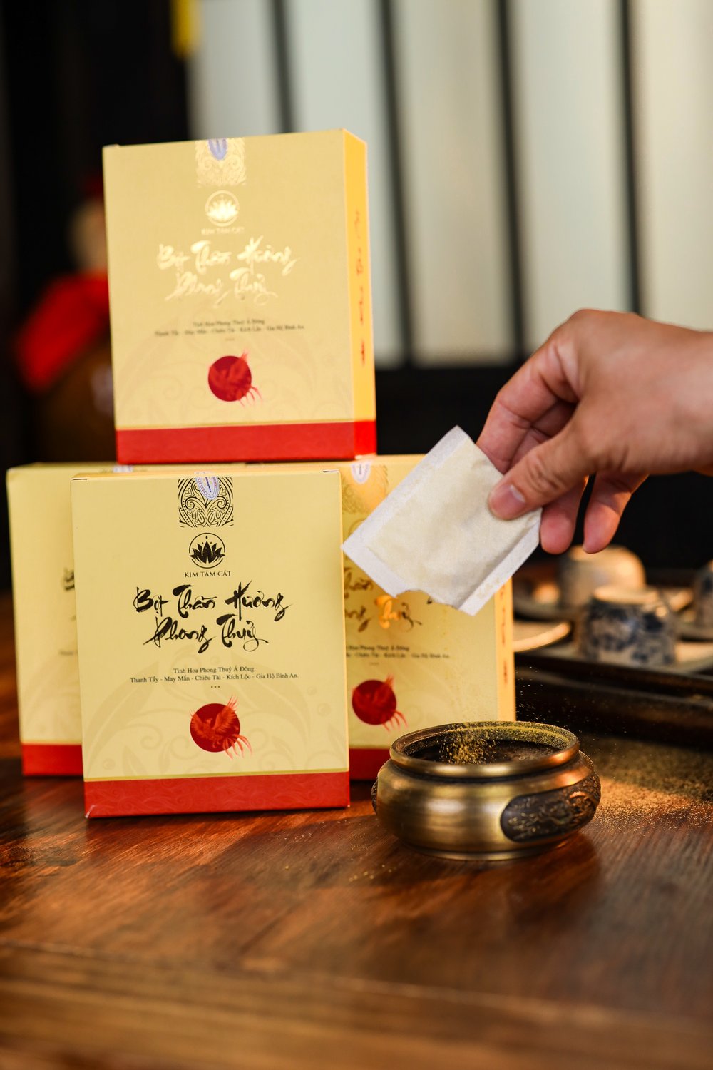 Tay cầm một túi bột Thần Hương bên cạnh hộp và lư đồng
